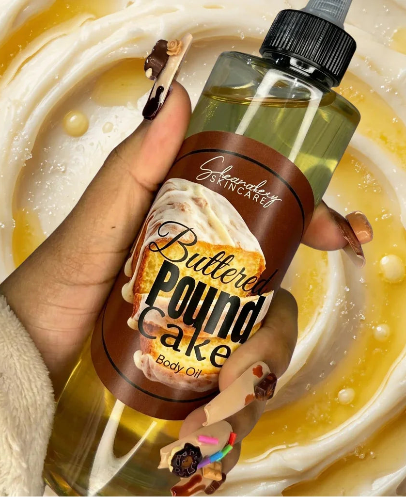Hand holding Buttered Pound Cake body oil bottle with dripping dessert-themed nails against a swirled icing background