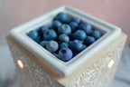 Blueberry-shaped wax melts in a decorative ceramic warmer