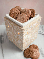 Ginger snap wax melts shaped like cookies in an ornate ceramic wax warmer