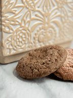 Ginger snap wax melts resembling cookies on a marble surface with decorative background.
