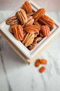 Pecan-shaped wax melts in a white ceramic dish on a marble surface